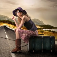 Фото с девушкой, сидящей на чемодане на дороге