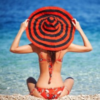 Летнее фото с девушкой в красном купальнике в шляпе на пляже